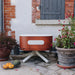 ALUVY SAM Original Low Brazier Terracota near a brick wall and planters