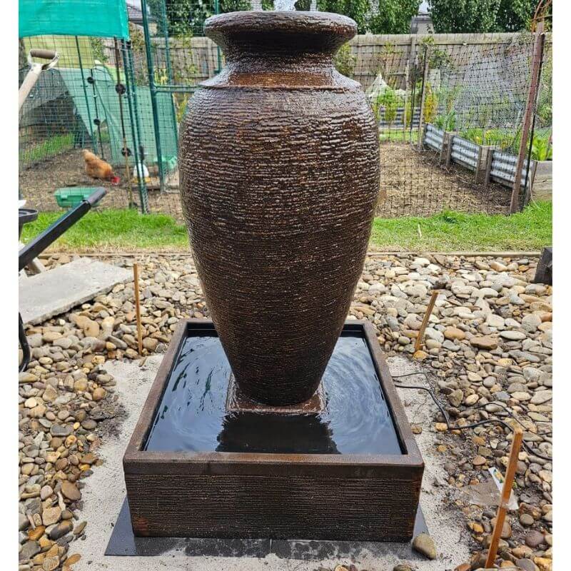 Amphora Fountain Rust with rocks on the ground