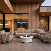 ExcoSmart Fire Table in Bone on the patio by the sofa