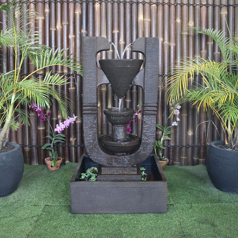 Galleria Imports Capri Water Fountain in Rust front view with garden surrounds