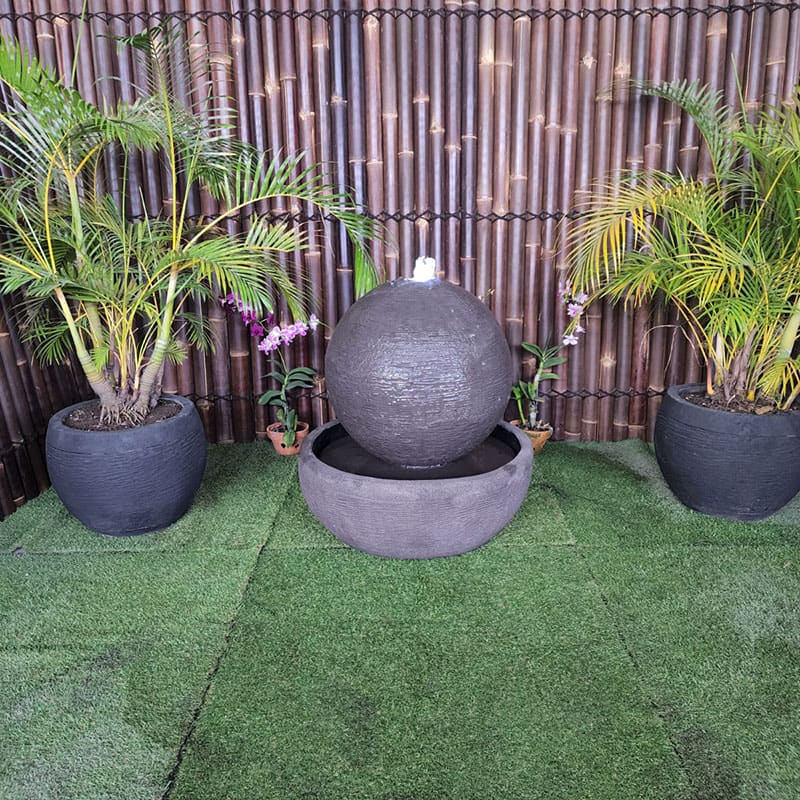 Galleria Imports Luna Ball Medium in grey surrounded by greenery