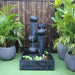 Streaming Pots Fountain by Galleria Imports in medium charcoal amongst plants and bamboo screen front view