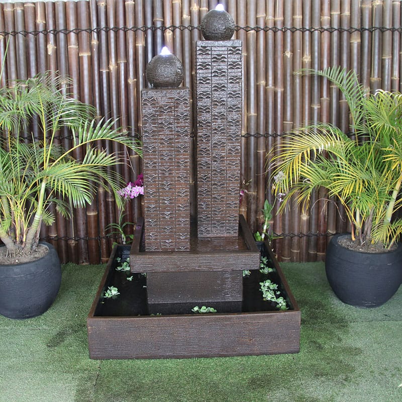 Galleria Imports Twin Column Fountain in rust front view in the garden