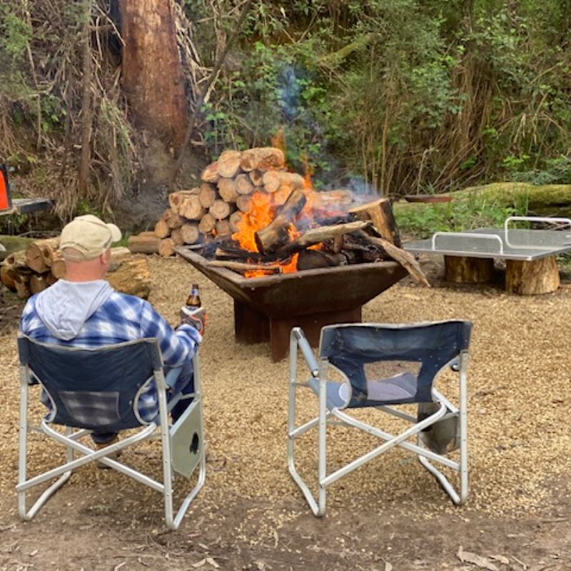 Pinnacle  Firepit with logs, trees and camping chairs