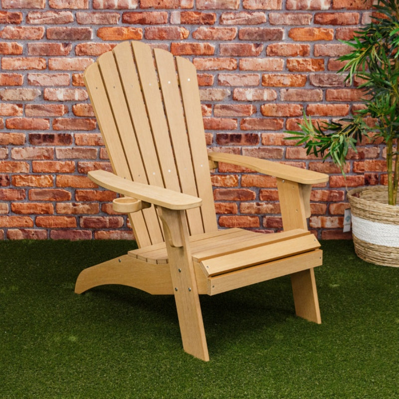 Winawood Adirondack Armchair- New teak chair on green carpet with brick wall behind.