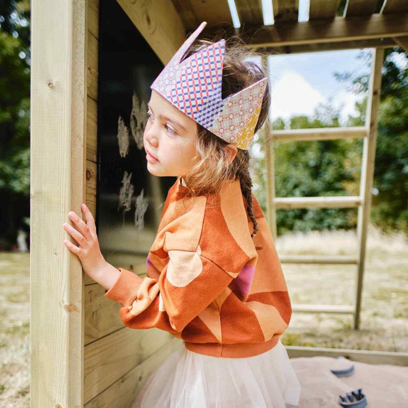 A girl hiding behind the Wooden lookout tower with ladder at the back